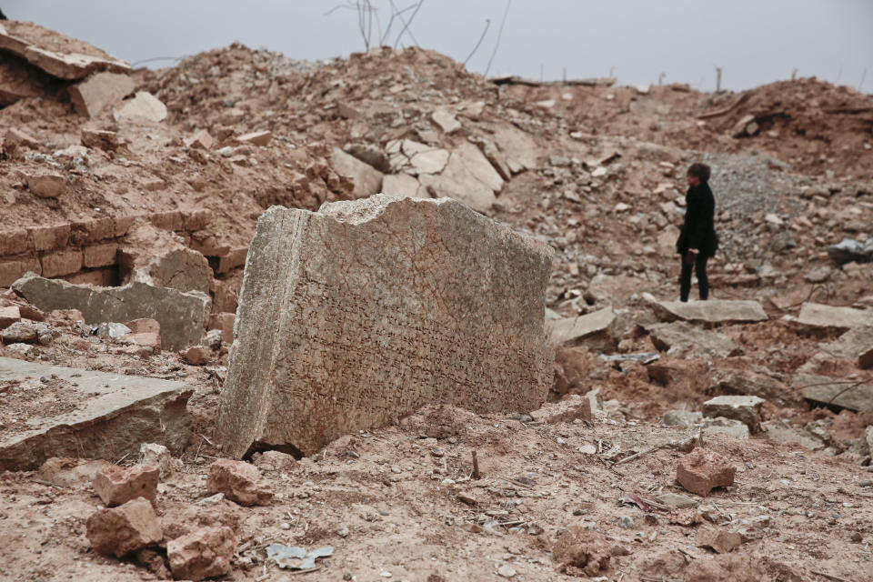 FILE - In this Wednesday, Dec. 14, 2016 file photo, a stone tablet with cuneiform writing in the foreground as UNESCO's Iraq representative Louise Haxthausen documents the damage wreaked by the Islamic State group at the ancient site of Nimrud, Iraq. France is trying to raise tens of millions of dollars from international donors who gathered Monday March 20, 2017, to protect cultural heritage sites threatened by war and the kind of destruction carried out by Islamic State militants. (AP Photo/Maya Alleruzzo, File)