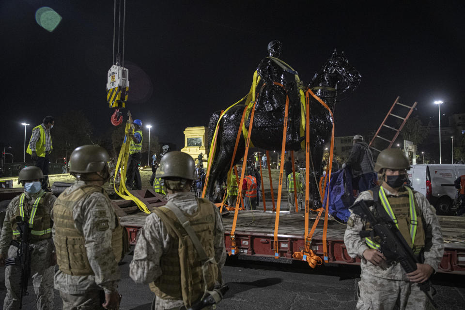 Soldiers stand guard as a statue of General Manuel Baquedano, a Chilean military officer and politician, is removed for restoration from Plaza Italia in Santiago, Chile, Friday, March 12, 2021. The statue located at the epicenter of the protests in Chile was removed for restoration with an order by the National Monuments Council. (AP Photo/Esteban Felix)