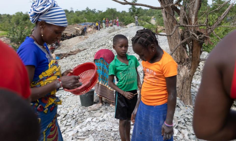 Women and children sift through rock and sediment looking for tiny gold deposits.