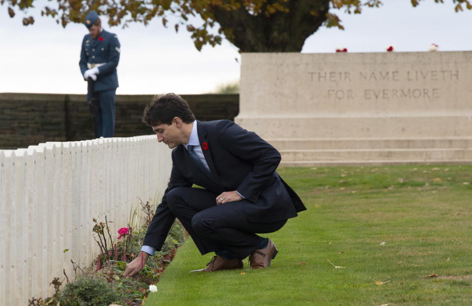 Canadian Prime Minister Justin Trudeau places a flower at a gravestone as he tours the Canadian Ceremony No. 2 near Vimy Ridge, France, Saturday Nov. 10, 2018. (Adrian Wyld/The Canadian Press via AP)