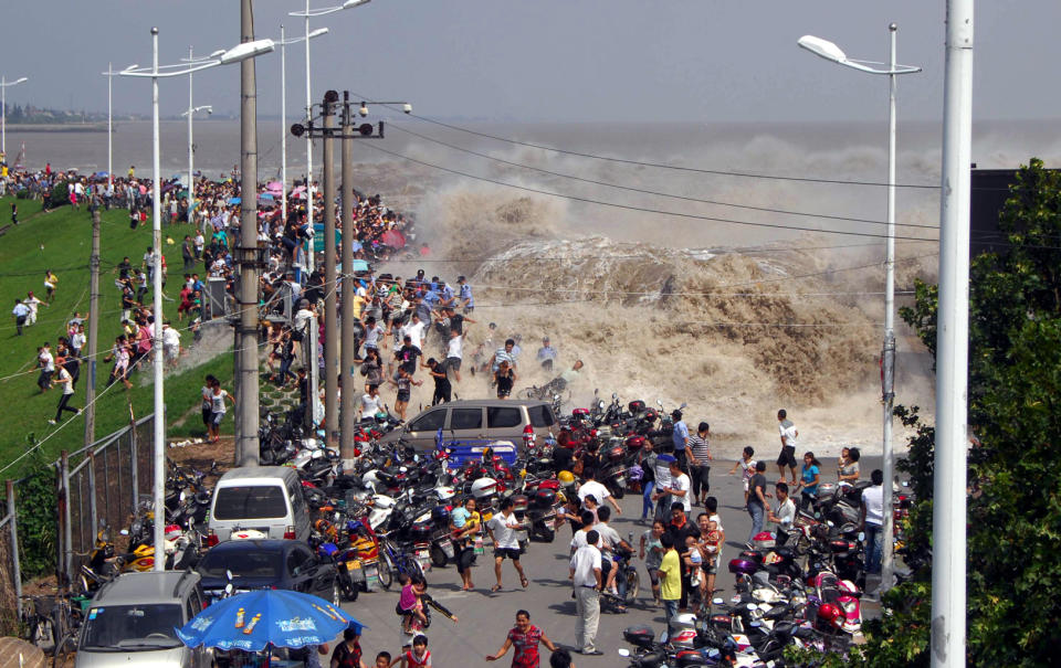 Spectators flee from the advancing wave to hit the Qiantang River, China.