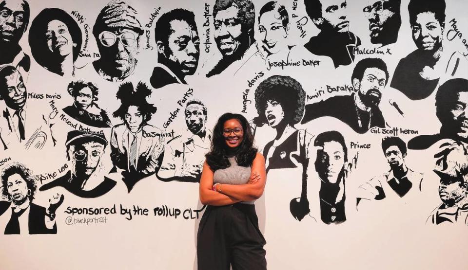 Cheryse Terry stands in front of a mural of Black history makers by Sade Black inside Archive.