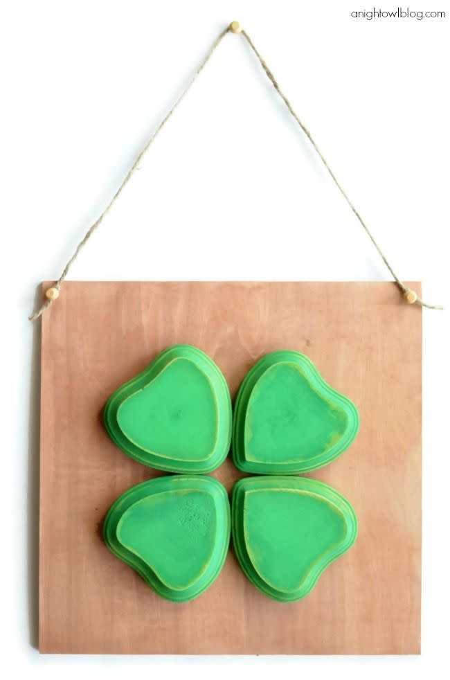 four leaf clover craft made with four green wooden hearts with the pointed end in the center, glued to a piece of birch wood