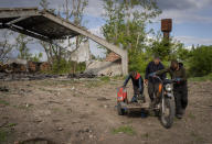 Villagers collect scrap metal from a shelled warehouse in the village of Malaya Rohan, Kharkiv region, Wednesday, May 18, 2022. (AP Photo/Bernat Armangue)