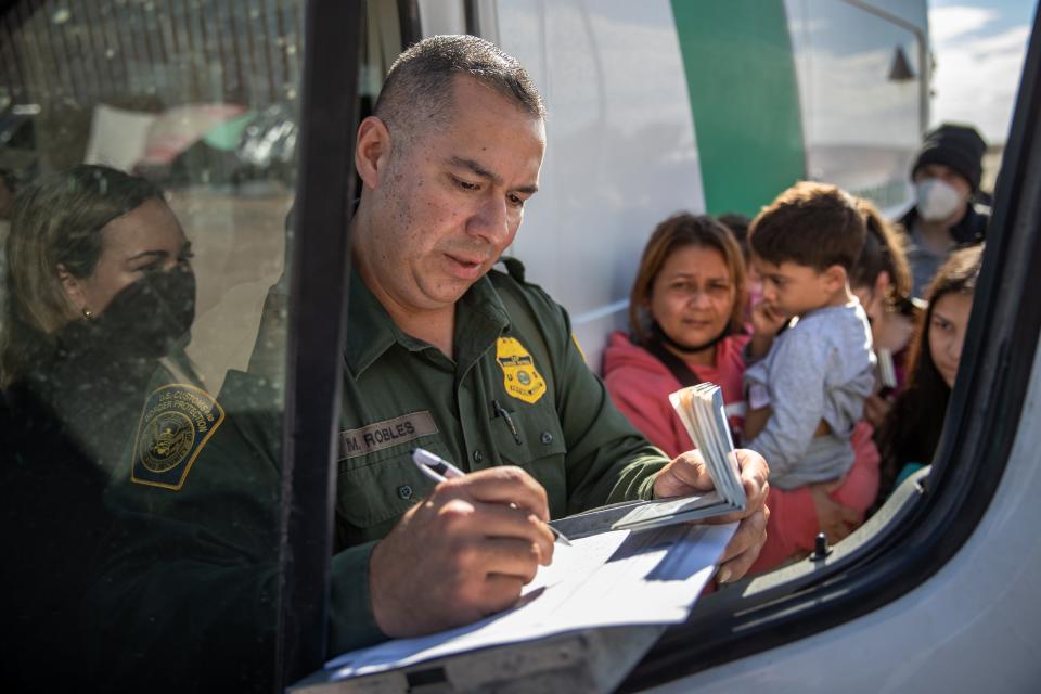 YUMA, ARIZONA - DECEMBER 09:  A U.S. Border Patrol agent checks passports before taking recently arrived immigrants to a processing center on December 09, 2021 in Yuma, Arizona. Women and children were eventually taken to the nearly full facility but many of the men had to sleep outside until the next day near the border fence. Yuma has seen a surge of migrant crossing in the last week, with many families trying to reach U.S. soil before the court-ordered re-implementation of the Trump-era "Remain in Mexico" policy. The policy requires asylum seekers to stay in Mexico for the duration of their U.S. immigration court process. (Photo by John Moore/Getty Images) ORG XMIT: 775749082 ORIG FILE ID: 1358276309