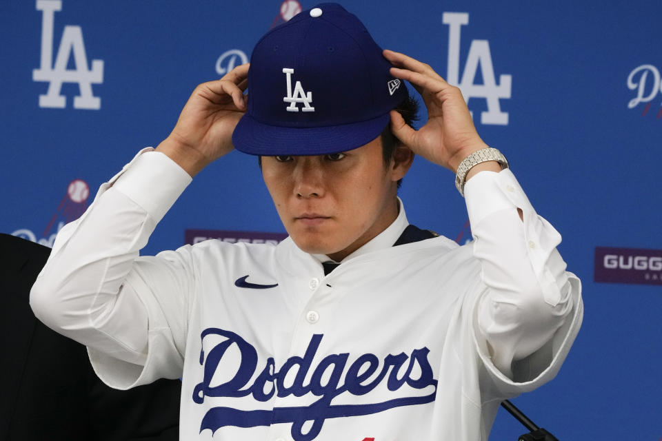 Yoshinobu Yamamoto se coloca la gorra durante la conferencia en que fue presentado como nuevo jugador de los Dodgers de Los Ángeles, el miércoles 27 de diciembre de 2023 (AP Foto/Damian Dovarganes)