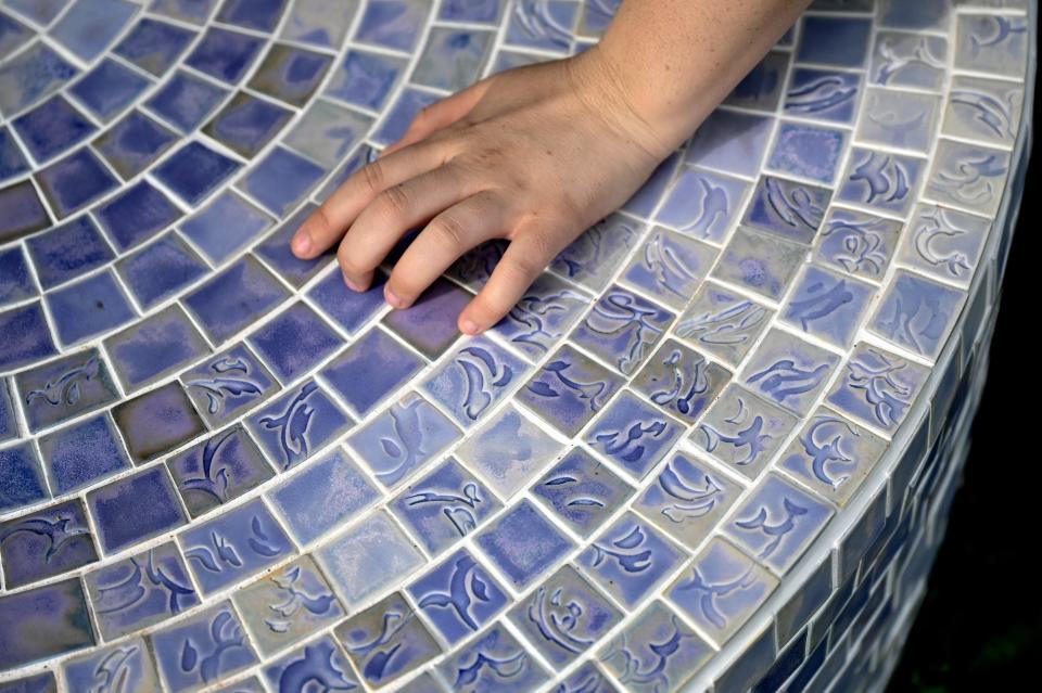 Hannah Tamiko Mackey, an artist included in this year's ArtPath public outside exhibition, talks about the tiles of her piece called "In Memory of a Pond" on Wednesday, June 1, 2022, in Old Town Lansing.