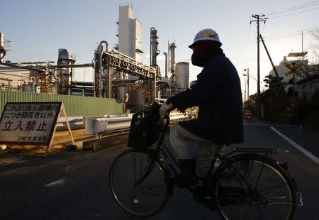 A worker cycles past a petro-industrial complex in Kawasaki near Tokyo December 18, 2014. REUTERS/Thomas Peter