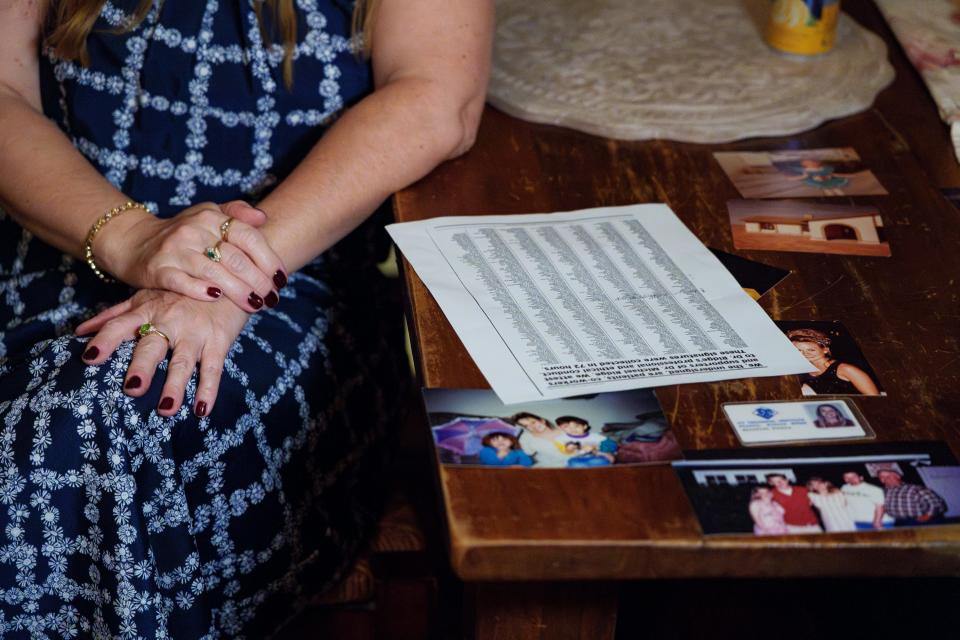 Meredith Younce sits at her dining room table, next to family photos and a printed list of names of Dr. Michael Ridge's supporters as she speaks to The Arizona Republic in her home on Sept. 28, 2023. A jury found Ridge not guilty in Younce's case against the doctor.