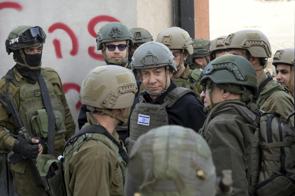 Israeli Prime Minister Benjamin Netanyahu, center, wears a protective vest and helmet as he receives a security briefing with commanders and soldiers in the northern Gaza Strip, on Monday, Dec. 25, 2023. (Avi Ohayon/GPO/Handout via AP)