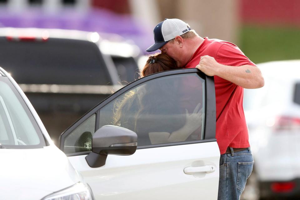 Family members are reunited at Memorial High School after being evacuated from the scene of a shooting in Tulsa, Okla.