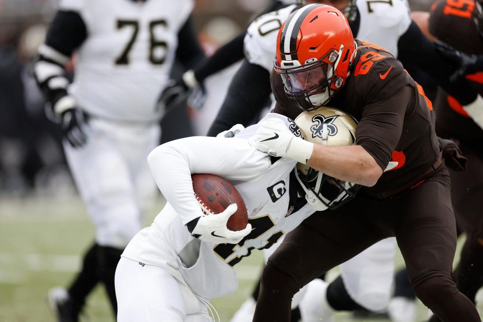 Cleveland Browns defensive end Chase Winovich (69) stops New Orleans Saints running back Alvin Kamara (41) during the first half of an NFL football game, Saturday, Dec. 24, 2022, in Cleveland. (AP Photo/Ron Schwane)