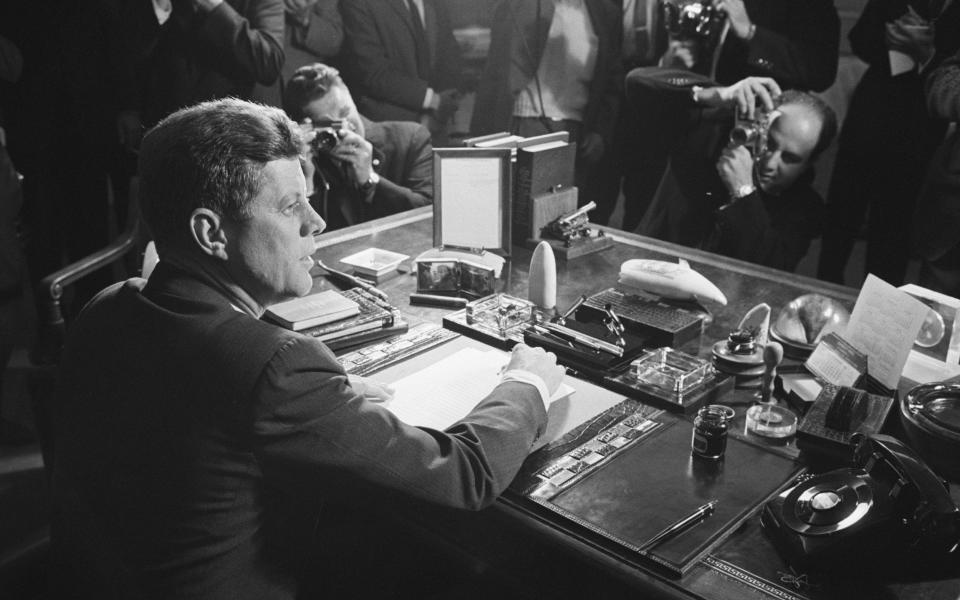 Kennedy behind his desk after signing the arms embargo against Cuba - Bettmann