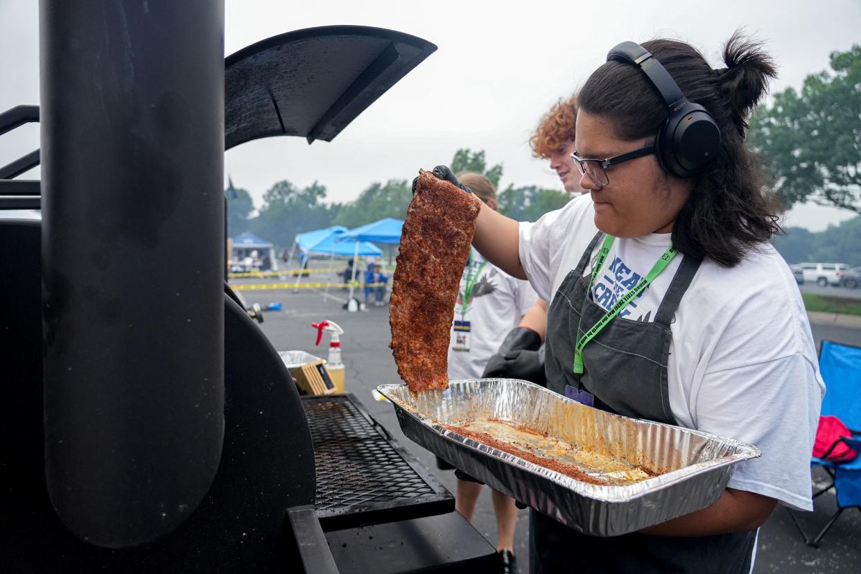 Emanuel Castillo adds ribs to the smoker at Cedar Creek High School's Meat the Creek team booth at the High School BBQ Inc. State Championship at Dell Diamond on Saturday. The 99 best competitive high school barbecue teams in the state tried to smoke their rivals at the cook-off in Round Rock.