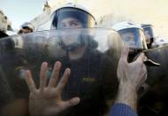 A protester holds a whistle as he places his hand against the shields of riot policemen guarding the parliament building during a rally calling on the government to clinch a deal with its international creditors and secure Greece's future in the Eurozone, in Athens, Greece, June 22, 2015. REUTERS/Yannis Behrakis