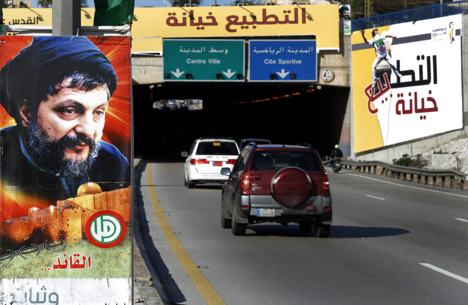 Cars pass next of a picture of Shiite Muslim spiritual leader, Imam Moussa Sadr, who disappeared on a trip to Libya in 1978, left, and a giant Arabic banner, right, that reads:"Normalization (with Israel) is treason," which set against the Arab economic development summit, at the airport highway where some of the Arab leaders who will attend the summit will pass by, in Beirut, Lebanon, Thursday, Jan. 17, 2019. The summit that Lebanon is hosting this weekend has been marred by controversy days before delegates arrive. (AP Photo/Hussein Malla)