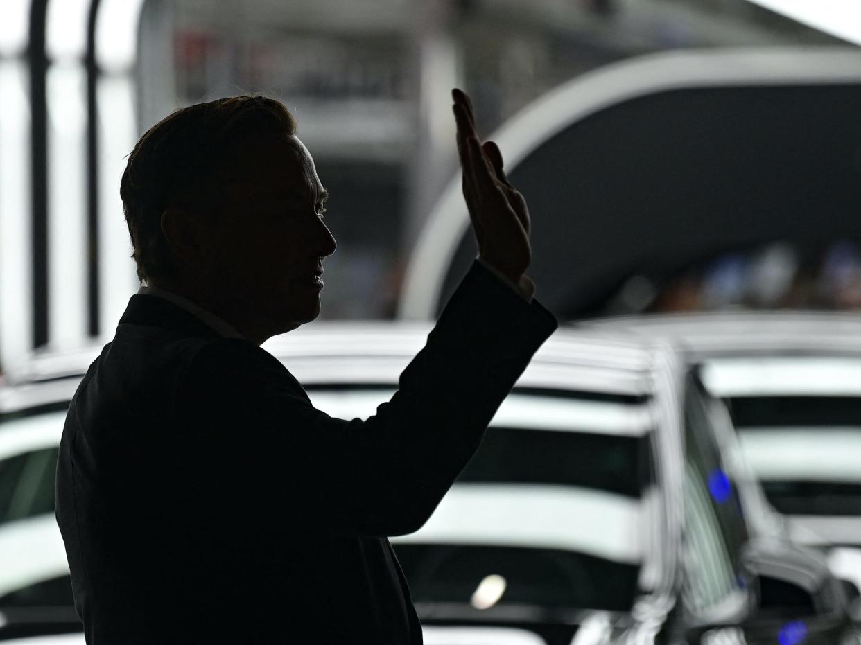 Elon Musk in silhouette waves at Tesla event