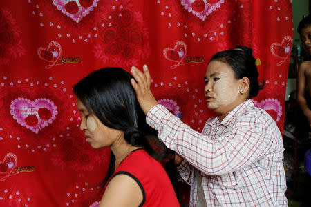 Thidar Win cuts Nwe Yee Win's hair she purchased for $18 in Yangon, Myanmar August 22, 2018. Picture taken August 22, 2018. REUTERS/Ann Wang
