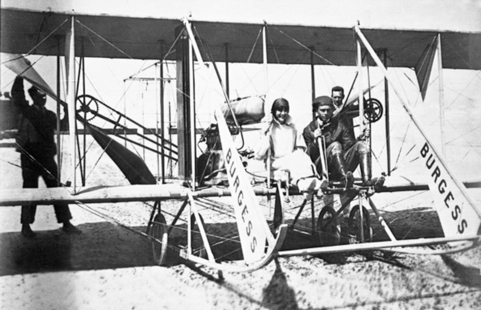 Phillips Ward Page pilots a Burgess-Wright Model F biplane in winter 1912 with a female passenger. Note the belt around her legs to keep her skirt in place. Page flew guests at the Clarendon Hotel.