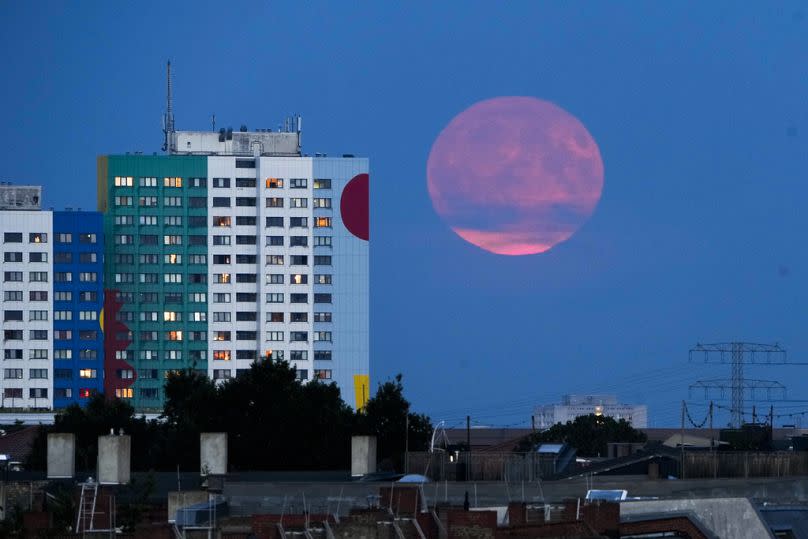 The supermoon rises from behind a resident building in Berlin, Monday, Aug. 19, 2024.