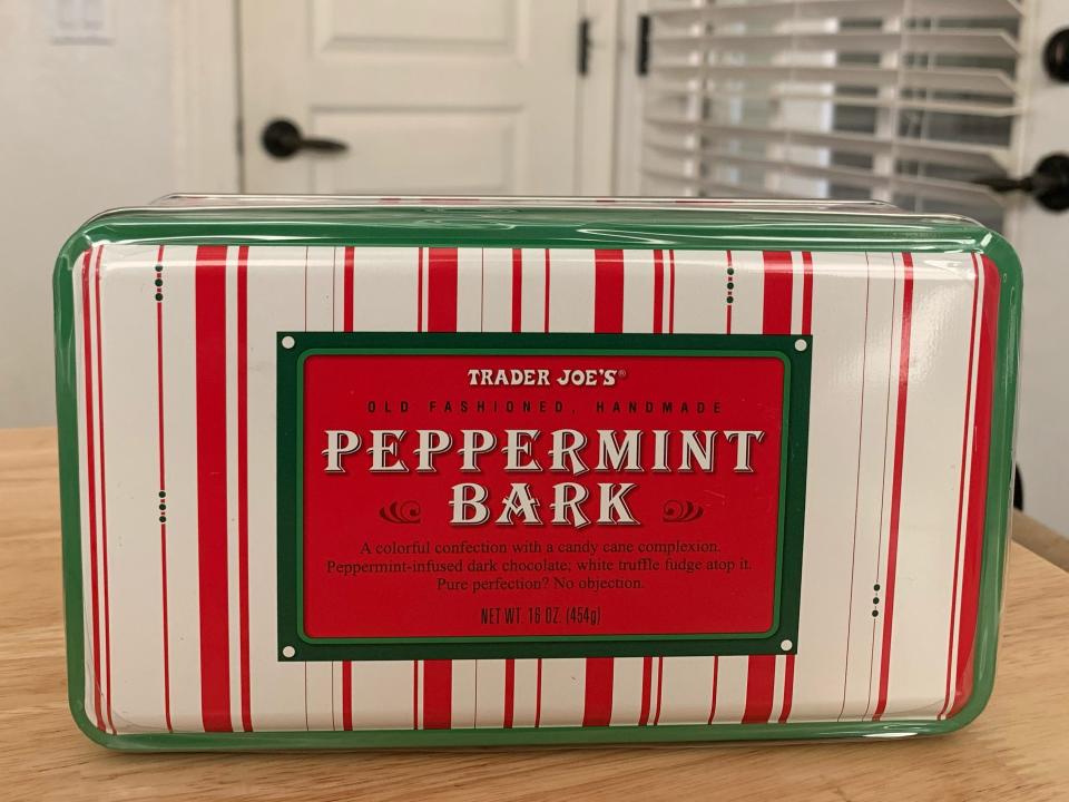 trader joes peppermint bark in cute red, white, and green tin on wood table