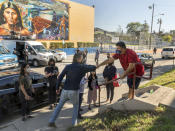 California Gov. Gavin Newsom, front left, greets resident Israel Ortiz, right, after Newsom visited a mobile vaccination site at Ramona Gardens Recreation Center in Los Angeles on Sunday, Feb. 21, 2021. California's new system of delivering and scheduling coronavirus vaccines is being rolled out in select counties. (AP Photo/Damian Dovarganes)