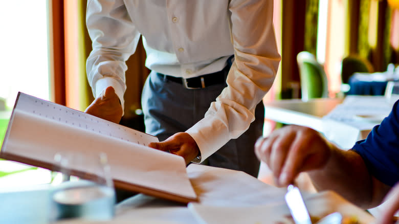 Waiter showing menu to diner