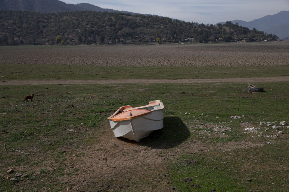 A boat sits parked the floor of the the Aculeo Lagoon lake bed, in Paine, Chile, Friday, Aug. 23, 2019. Officials in Chile say that the capital city and its outskirts are suffering from the worst drought in decades. (AP Photo/Esteban Felix)