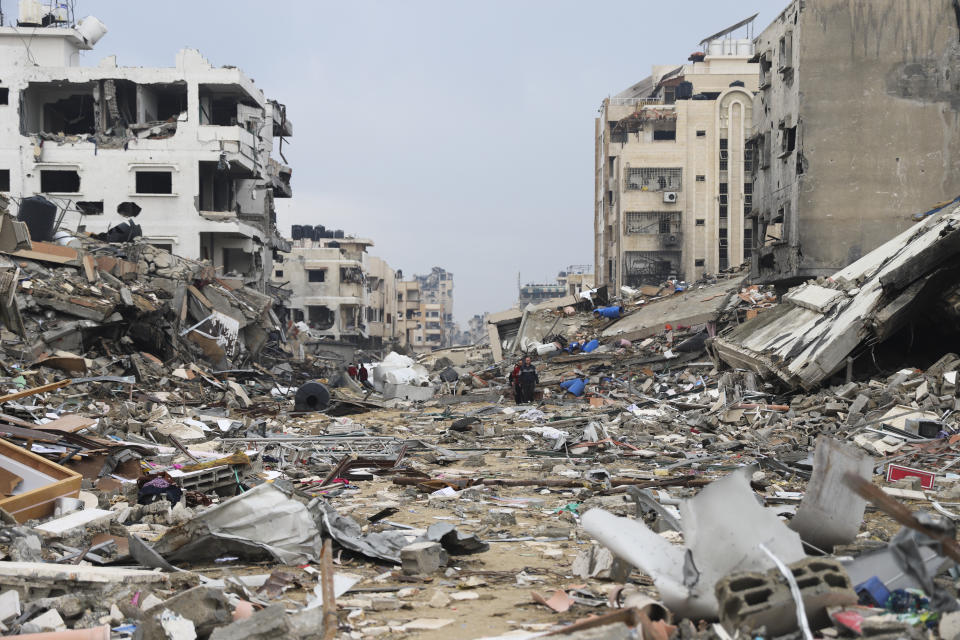 Palestinians walk past the building destroyed in the Israeli Bombardment of the Gaza Strip in Gaza City on Wednesday, Jan. 3, 2024. (AP Photo/Mohammed Hajjar)