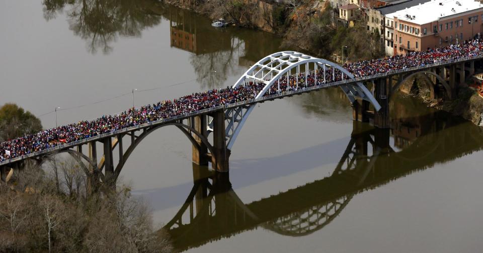 FILE - In this Sunday, March 8, 2015, file photo, a large crowd moves in a symbolic walk across the Edmund Pettus Bridge, in Selma, Ala., to mark the 50th anniversary of "Bloody Sunday," a civil rights march in which protestors were beaten, trampled and tear-gassed by police at the bridge. Organizers of the annual civil rights celebration and organizers of a Civil War battle re-enactment are upset the city is asking them to pay tens of thousands of dollars to cover the costs of police and fire protection and cleanup. (AP Photo/Butch Dill, File)