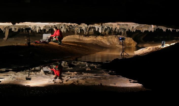 Stephen Alvarez, founder of the Ancient Art Archive, preparing to photograph Native American art on the ceiling of a cave in Alabama. His reflection is seen in a pool in the cave.
