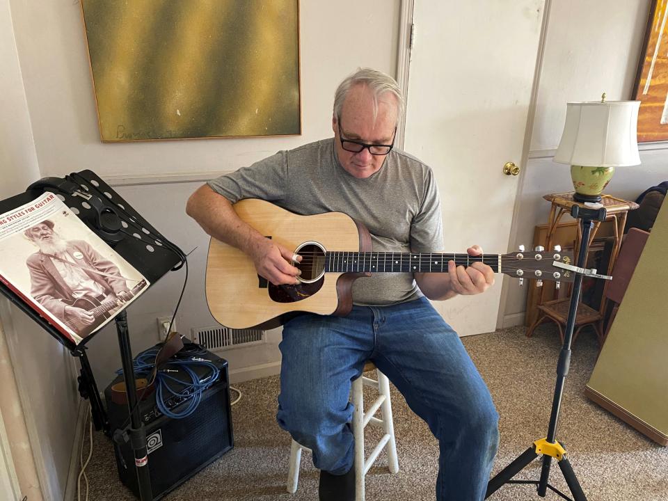 Bob Dorobis plays his guitar at home in Middletown, N.J., on Dec. 4, 2022. Dorobis redoubled his efforts to learn fingerpicking during the pandemic. (Jeanann Dorobis via AP)