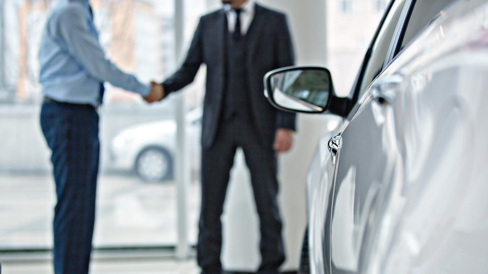 Handshake between two business people in a car showroom.