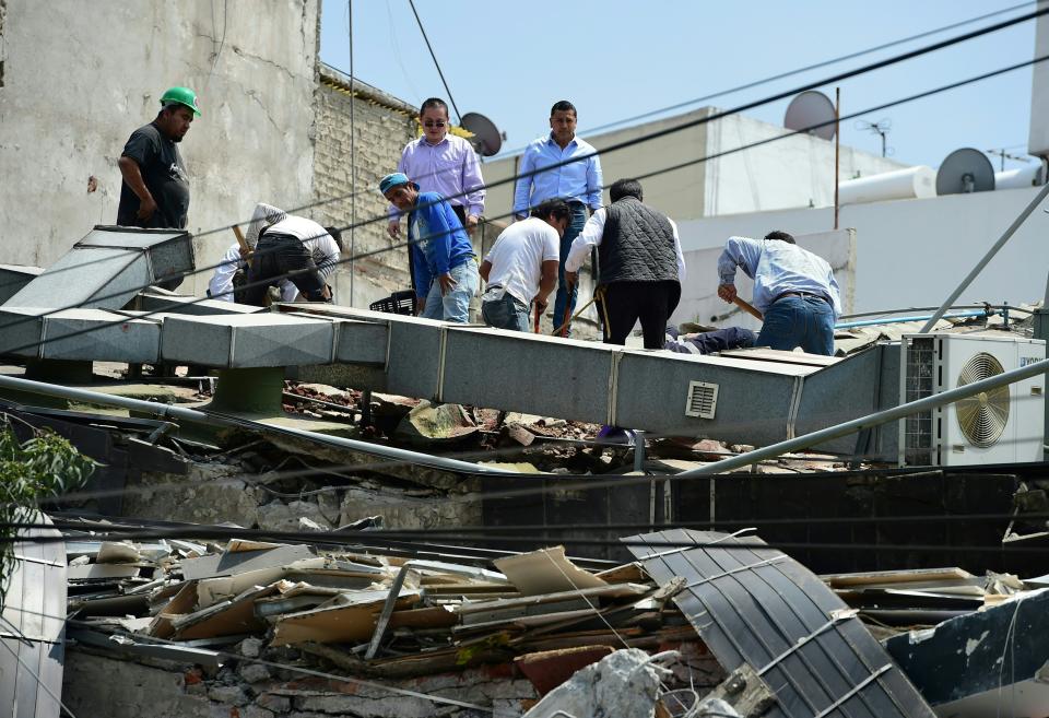 People look through the debris of a building.