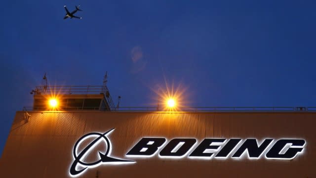 Plane flies over a building with a Boeing logo