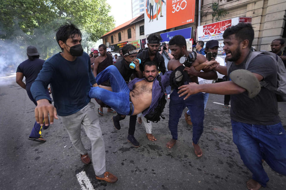 An injured student is carried by colleagues as police fire tear gas and water cannons to disperse protesting members of the Inter University Students Federation during an anti government protest in Colombo, Sri Lanka, Thursday, May 19, 2022. Sri Lankans have been protesting for more than a month demanding the resignation of President Gotabaya Rajapaksa, holding him responsible for the country's worst economic crisis in recent memory. (AP Photo/Eranga Jayawardena)