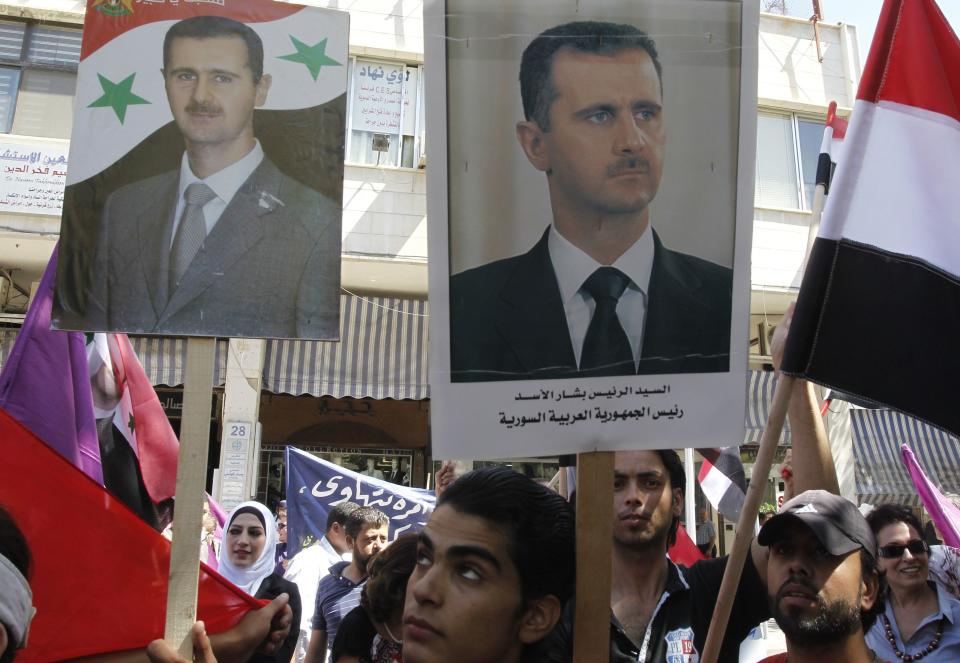 Supporters of Syria's President Bashar al-Assad wave his posters during a rally in front of the parliament building under the slogan "No aggression on Syria", in Damascus September 17, 2013. REUTERS/Khaled al-Hariri (SYRIA - Tags: POLITICS CONFLICT CIVIL UNREST)