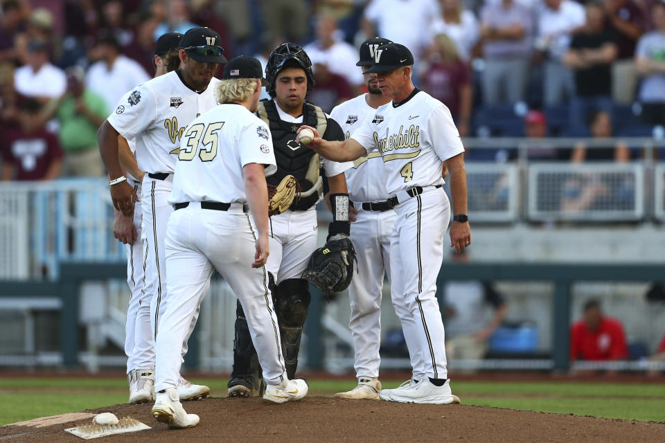 Vanderbilt head coach Tim Corbin (4) hands the ball to pitcher Chris McElvain (35) during the fifth inning against Mississippi State in Game 3 of the NCAA College World Series baseball finals, Wednesday, June 30, 2021, in Omaha, Neb. (AP Photo/John Peterson)