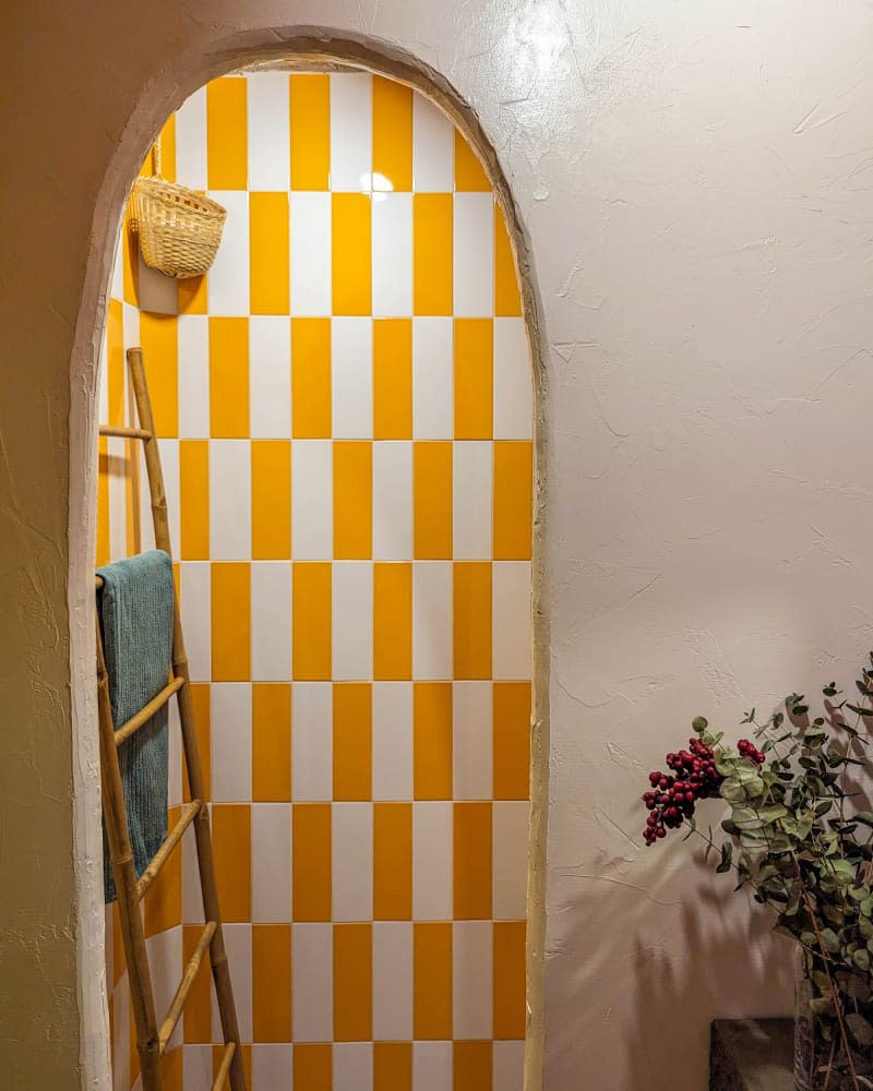 view into bathroom with orange and white checkered wall and ladder with towels