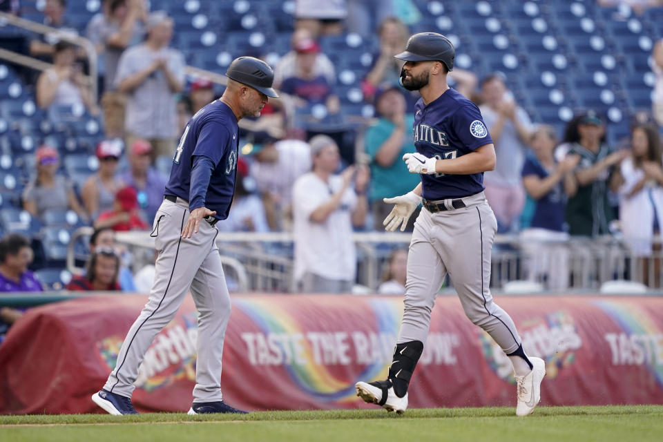 Seattle Mariners' Jesse Winker, right, rounds the bases past third base coach Manny Acta after hitting a solo home run in the sixth inning of the second game of a baseball doubleheader against the Washington Nationals, Wednesday, July 13, 2022, in Washington. (AP Photo/Patrick Semansky)