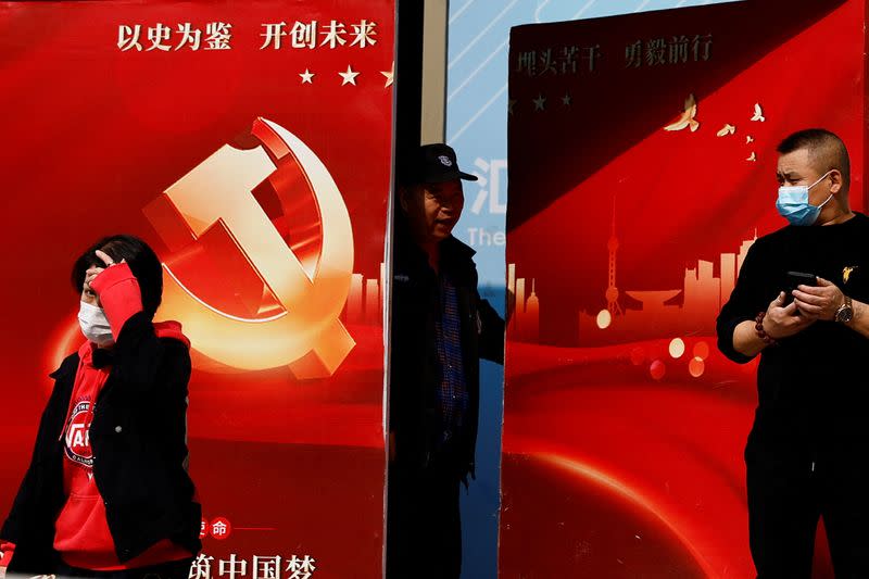 Security guard opens a door attached with a poster welcoming the 20th National Congress of the Communist Party of China, in Beijing