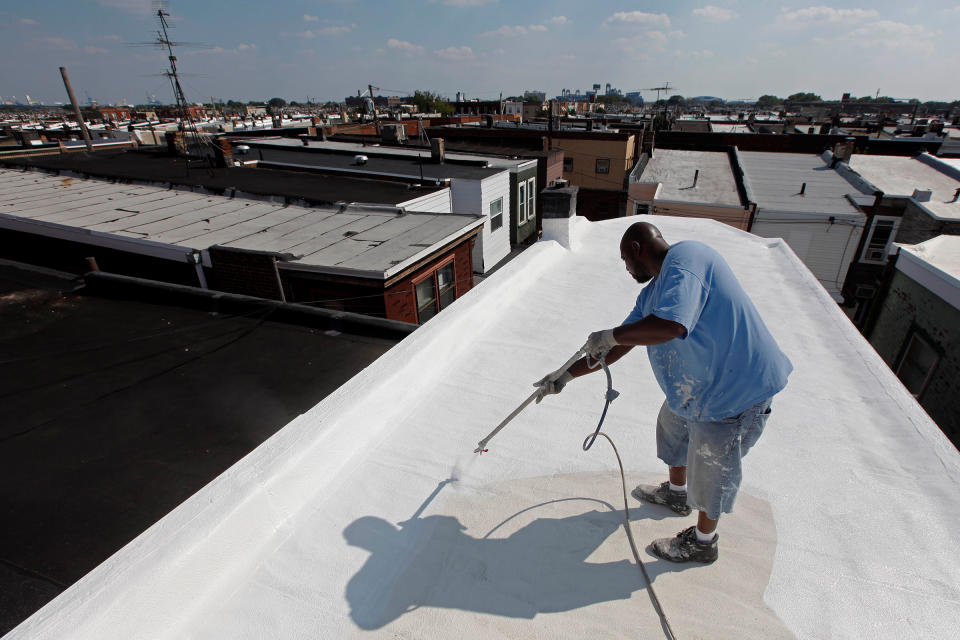 James Peterson with Bio Neighbors applies a coating of Acrymax to the roof of a row home in Philadelphia in August 2010. The idea of painting roofs white has become something of a social movement, one that many believe could be a huge help in stopping global warming.<span class="copyright">Matt Rourke—AP</span>