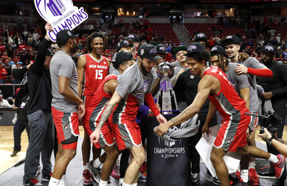 New Mexico players celebrate after defeating San Diego State in an an NCAA college basketball championship game at the Mountain West Conference tournament Saturday, March 16, 2024, in Las Vegas. New Mexico guards Jaelen House, center left, and Tru Washington, center right, dance in front of the trophy. (AP Photo/Steve Marcus)