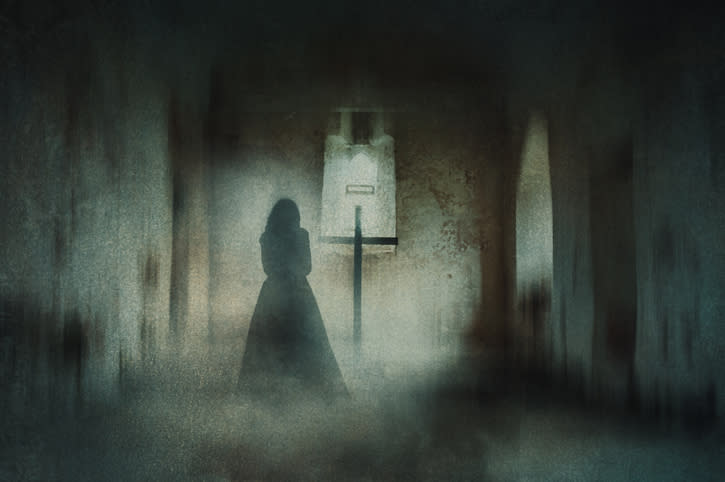 Silhouetted figure in a hallway facing a cross, eerie atmosphere