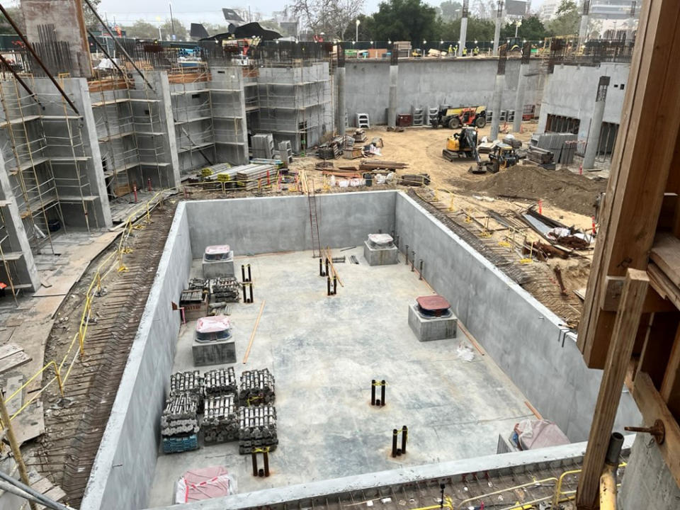 a building's cement foundation surrounded by dirt and construction equipment