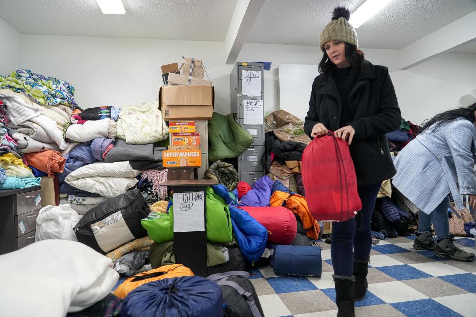 Tara McLeod stacks donated sleeping bags at the Sunrise Homeless Navigation Center on Sunday.