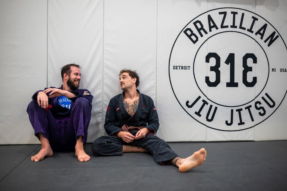 John Simmons, left, a purple belt, and Zach Mabey, a brown belt, in Brazilian jujitsu, talk with one another during a training session inside the 313 Brazilian Jiu Jitsu gym in Detroit on Tuesday, Aug. 29, 2023. Simmons and Mabey started practicing Brazilian jujitsu around the same time.