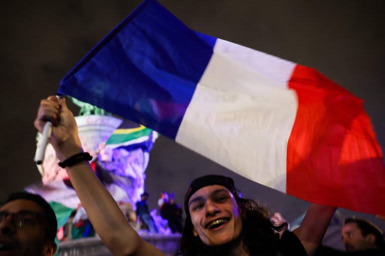 Un votante sostiene una bandera francesa durante un mitin nocturno electoral tras los primeros resultados de la segunda vuelta de las elecciones legislativas de Francia en la Place de la Republique en París el 7 de julio de 2024.