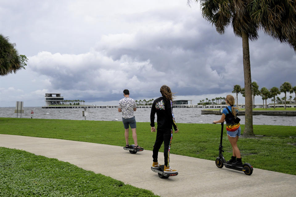 People ride along the bayfront as an outer band of Hurricane Ian approaches and kicks up the surf at Vinoy Park, Tuesday, Sept. 27, 2022, in St. Petersburg, Fla. (AP Photo/Phelan M. Ebenhack)