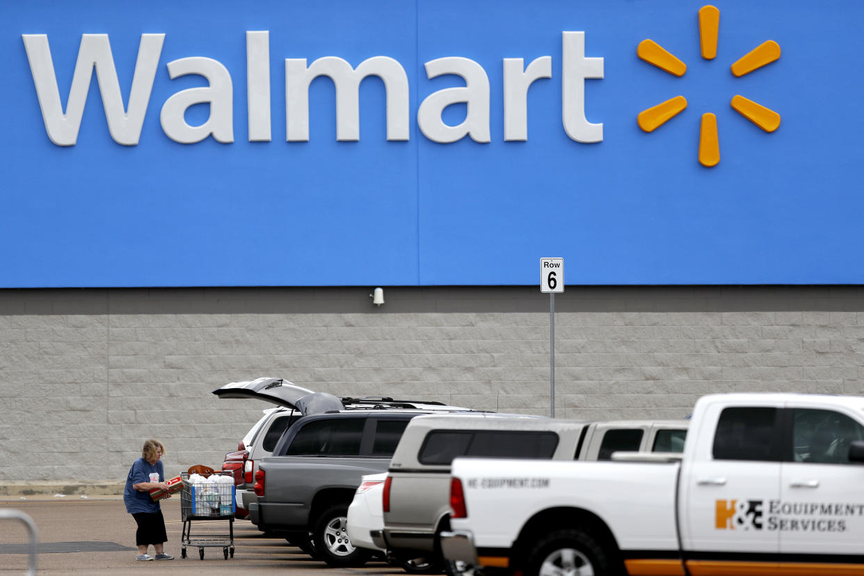 FILE - In this March 31, 2020 file photo, a woman pulls groceries from a cart to her vehicle outside of a Walmart store in Pearl, Miss. Walmart is teaming with the General Motors' Cruise autonomous vehicle unit to test automated package delivery in Arizona. (AP Photo/Julio Cortez, File)